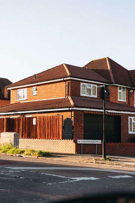 A black and white illustration of a house with a prominent sign reading 'Mortgage' hanging from the front, set against a bright blue background featuring floating percentage symbols. The house feature
